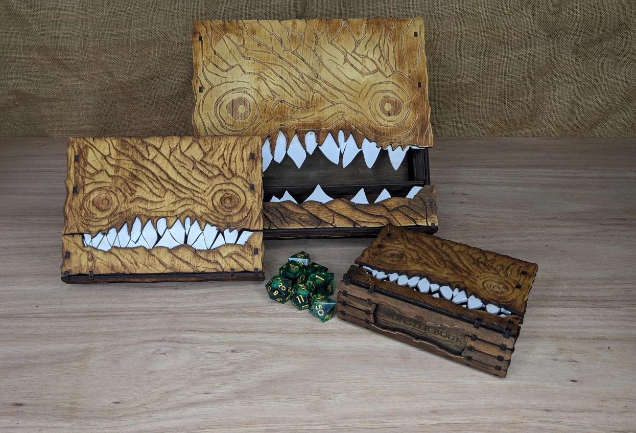 Handcrafted wooden monster book boxes with carved teeth and creature details, inspired by fantasy and tabletop role-playing games.